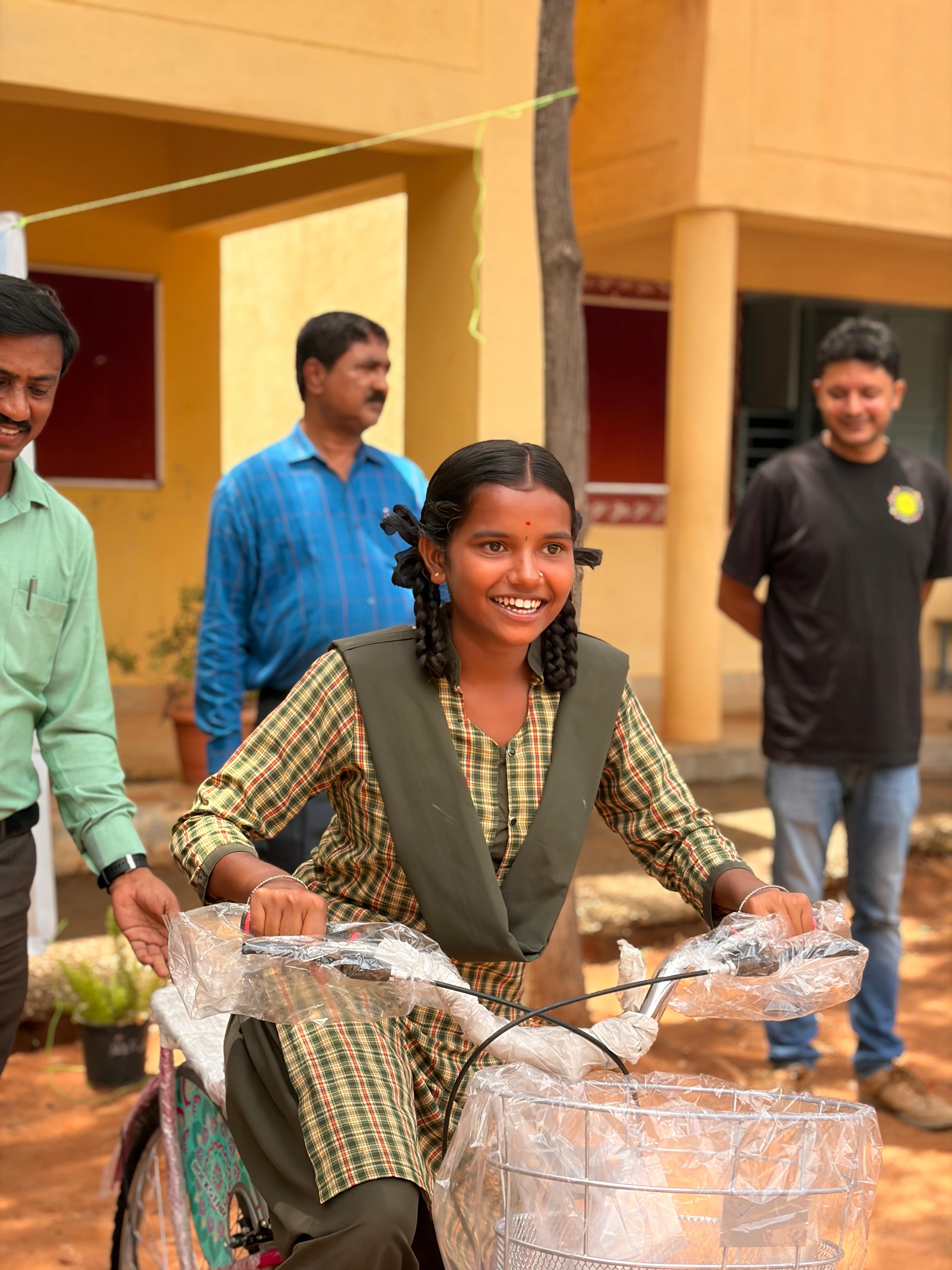 School staff and volunteers hand over a bicycle to a student