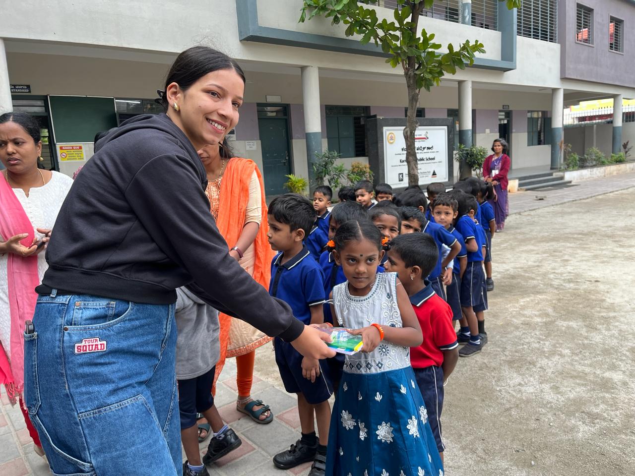 Volunteer distributing educational kits to young students at school