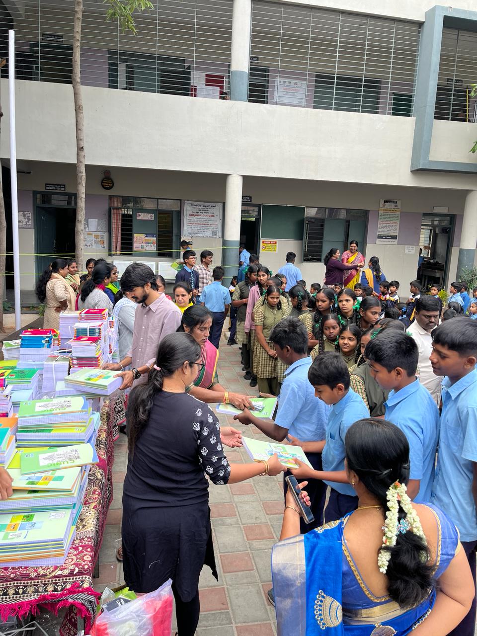 Staff distributing notebooks to school children during an educational event