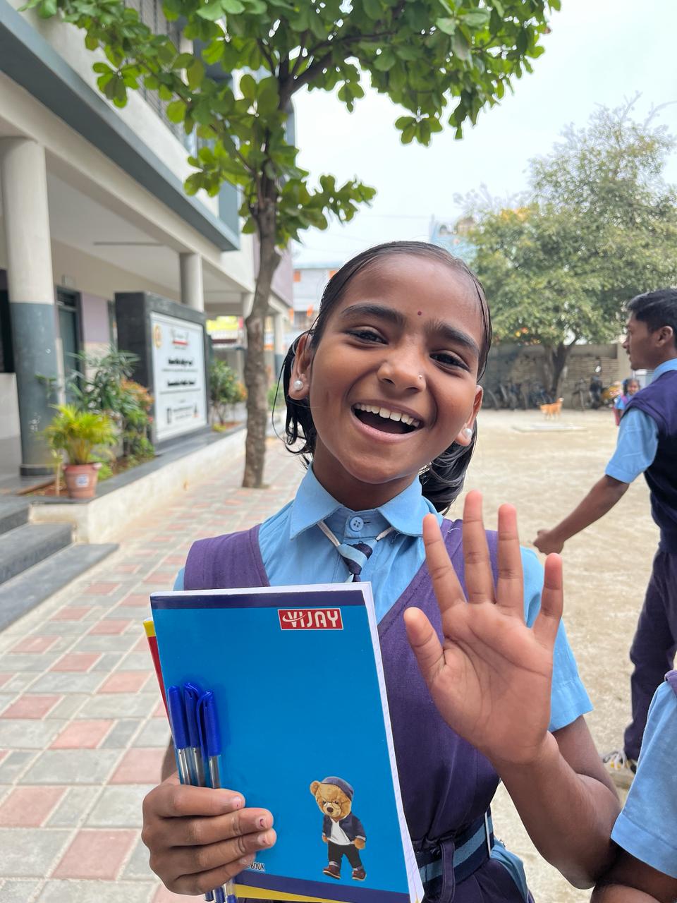 A happy young student holding notebooks and pens at school.