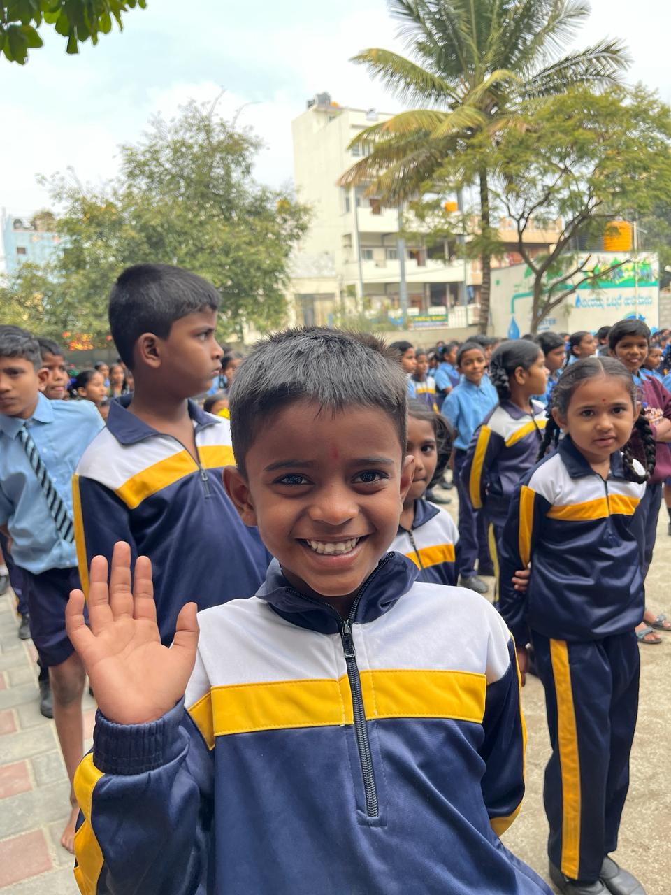 Happy young schoolboy smiling and waving in his school uniform