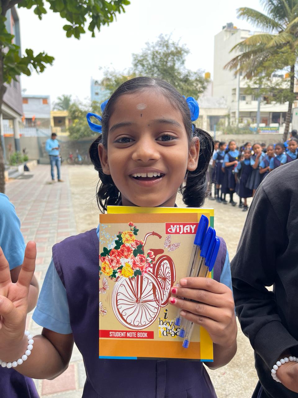 Smiling young student holding new notebooks and pens outdoors