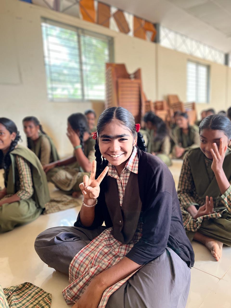 Smiling school girl in uniform sitting with fellow students