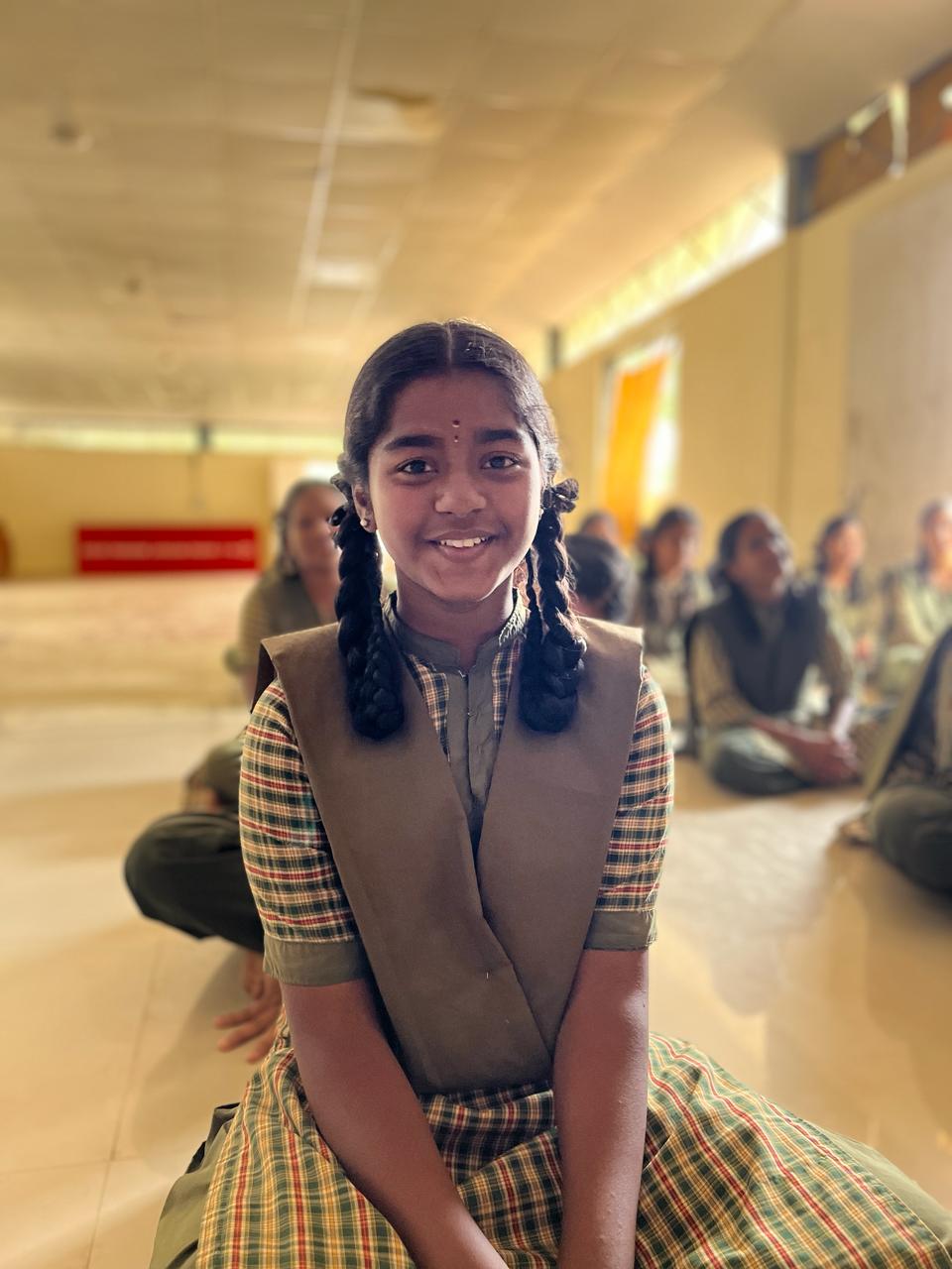A smiling young girl in uniform attending school classes