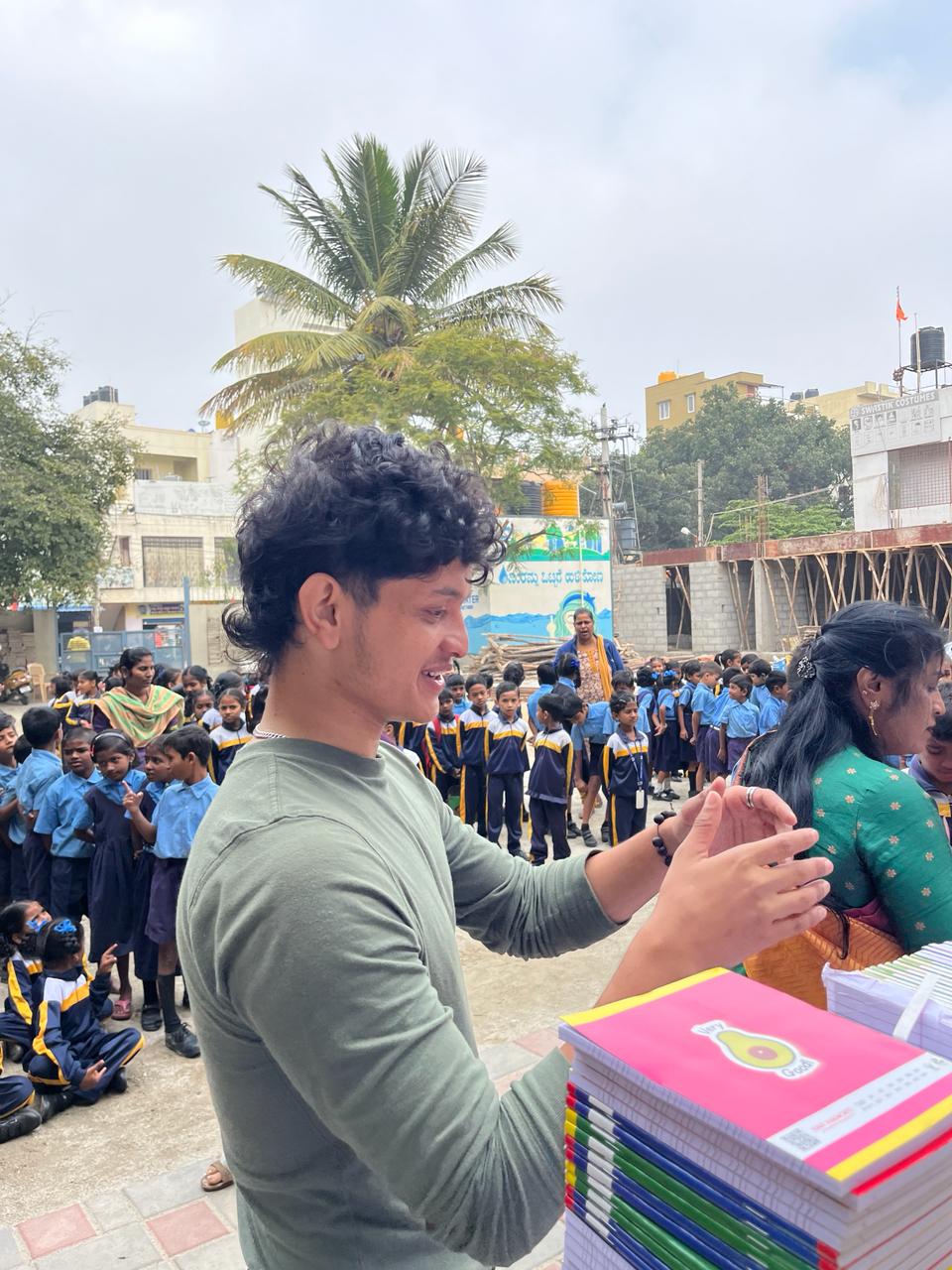 Volunteer distributing notebooks to children at a local school
