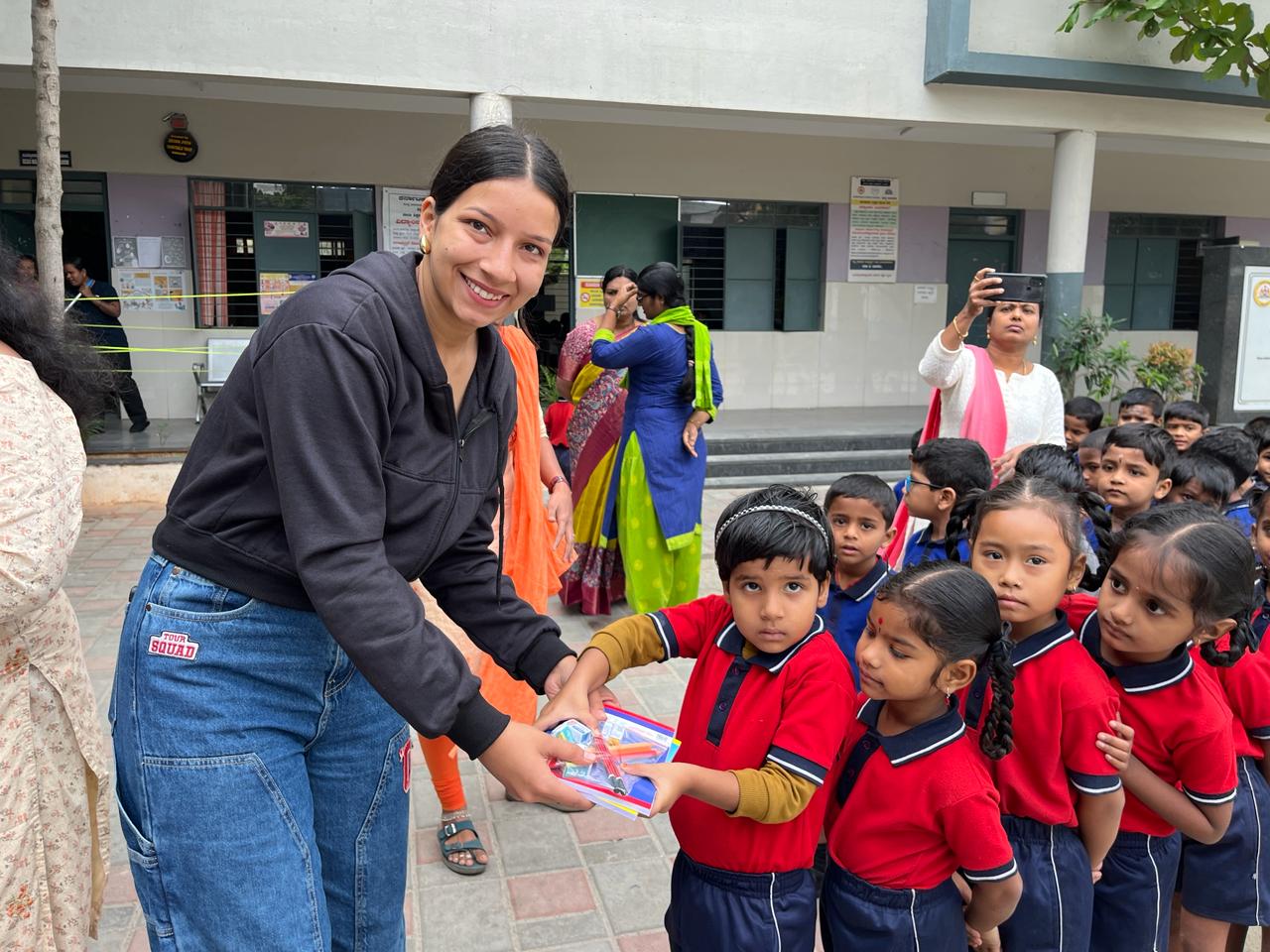 A volunteer distributing stationery kits to young school children