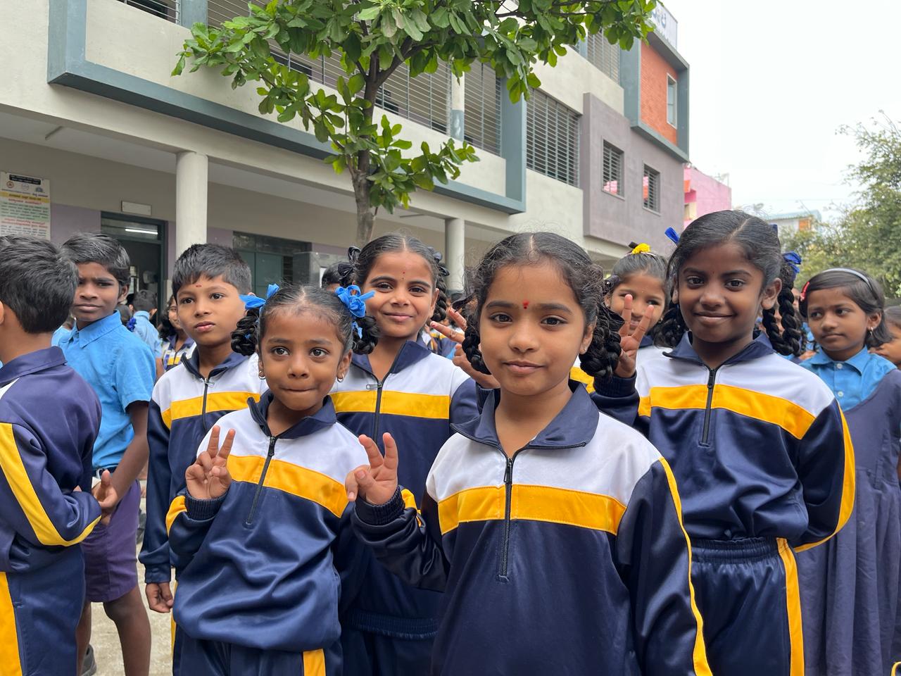 Young students in school uniforms smiling together outdoor.